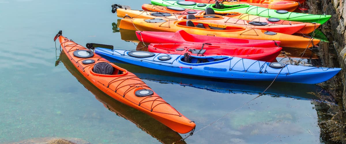 a row of colorful fiberglass kayaks for rent in a small Massachusetts harbor