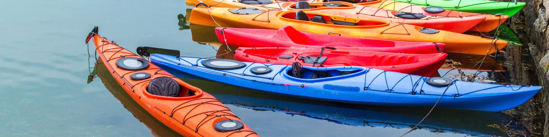 a row of colorful fiberglass kayaks for rent in a small Massachusetts harbor