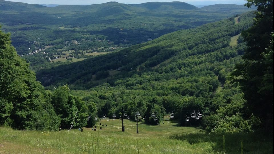 A valley with rolling hills, a small town in the distance, and a clear sky.