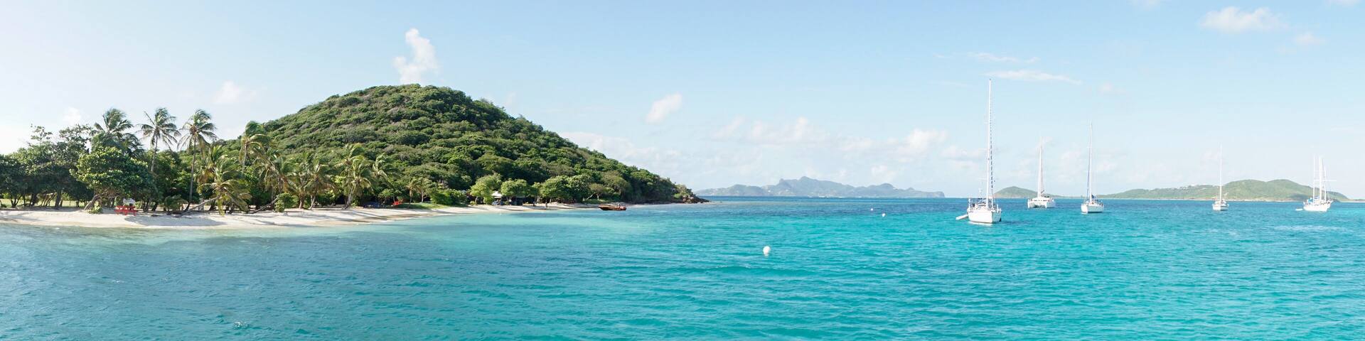 Tropical ocean and beach with sail boat yacht in the Tobago Cays, Saint Vincent and the Grenadines, Caribbean.