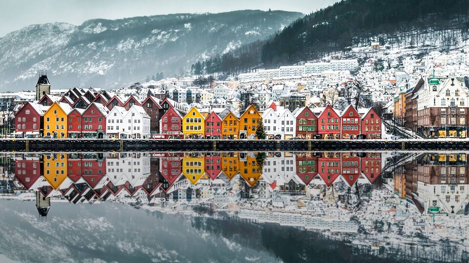 A snowy town with colorful houses and a mountain in the background.