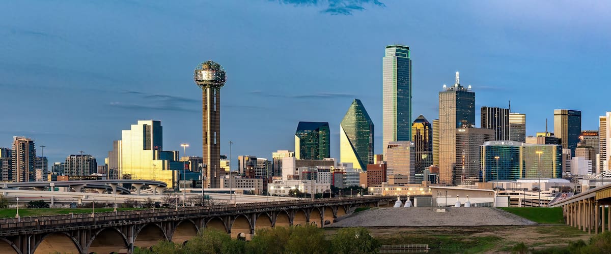 A city skyline with modern skyscrapers, a distinctive tower, and a bridge.
