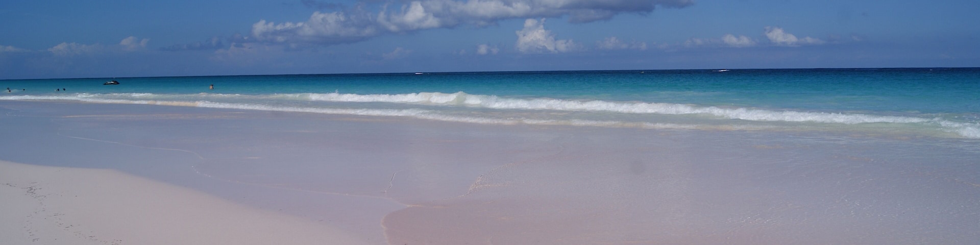 Una playa con cielo despejado y olas suaves.