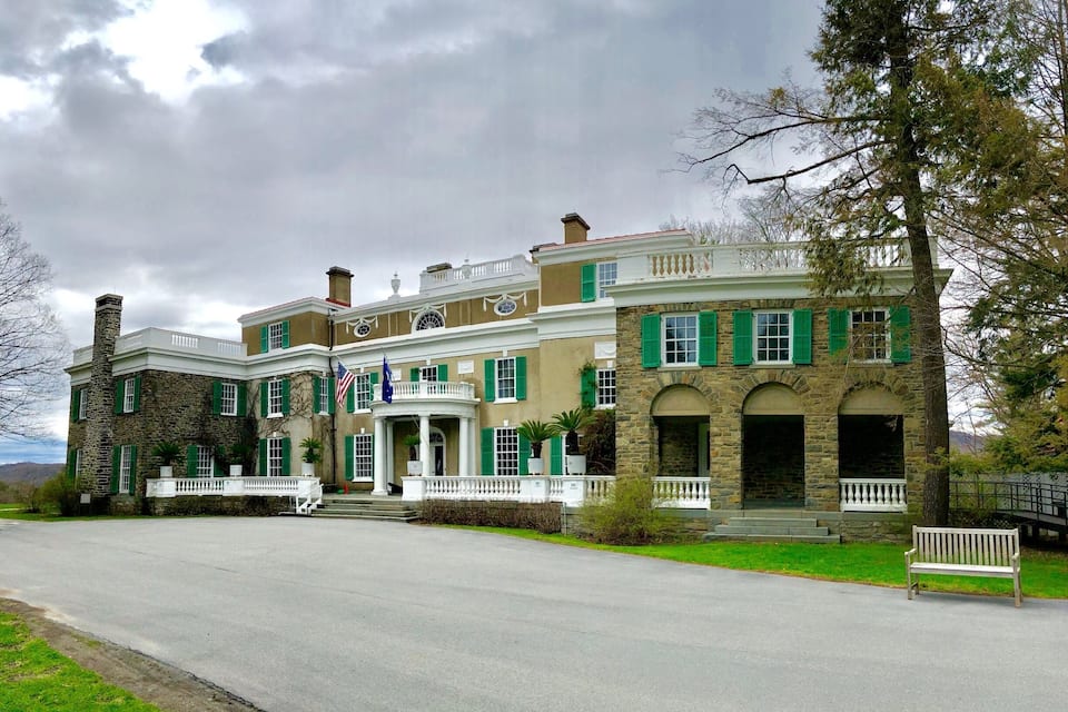 A large, historic building with green shutters and a white porch.