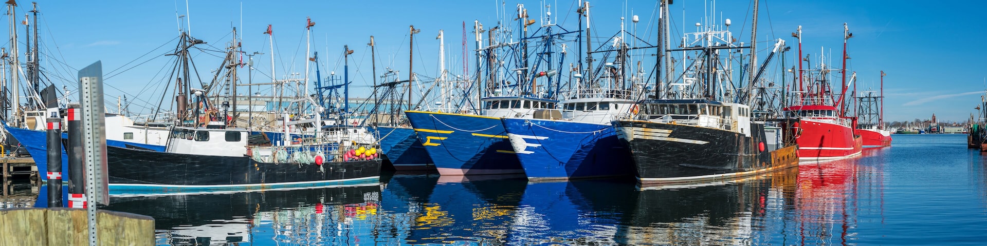A marina with several fishing boats docked, including a prominent red and white vessel.