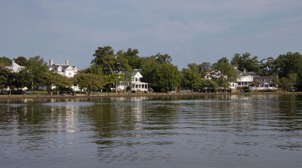 A calm lake with white houses and trees along the shore.