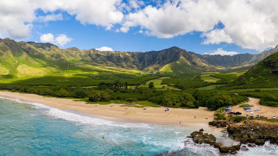 A coastal landscape with a beach, mountains, and a clear sky.