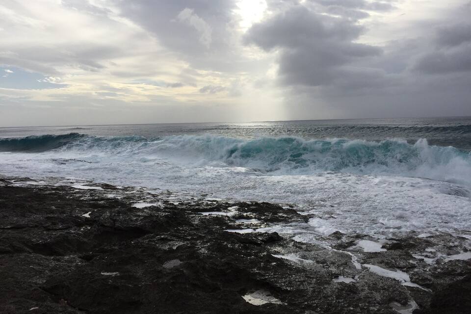 Un rivage rocheux où les vagues s’écrasent contre les rochers sous un ciel nuageux.