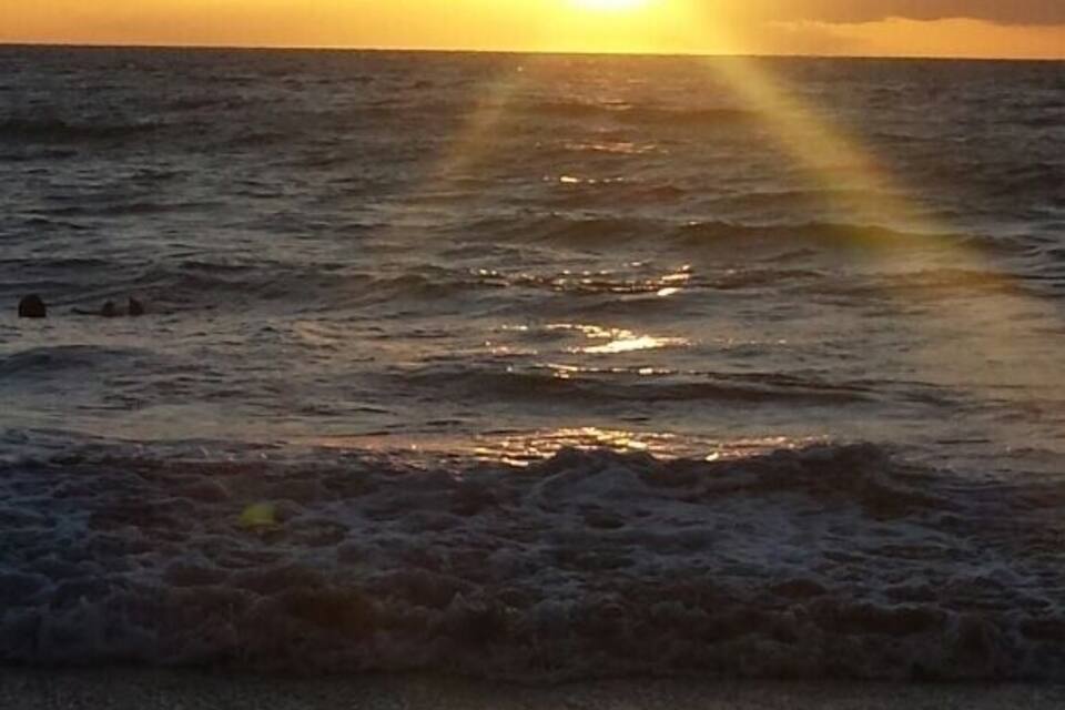A sunset over the ocean with sunlight reflecting on the water.