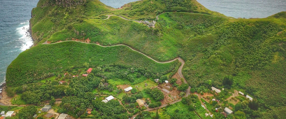 An aerial view of a lush green island with winding roads and scattered buildings.
