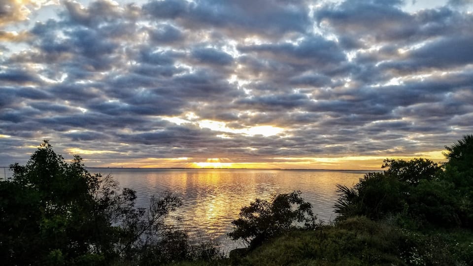 A sunset over a body of water with a cloudy sky.