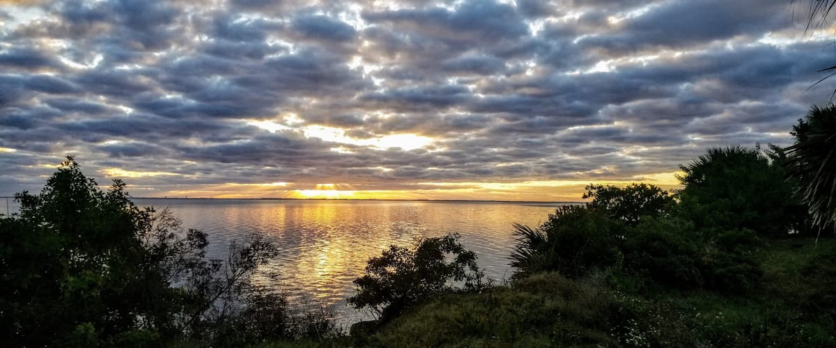A sunset over a body of water with a cloudy sky.