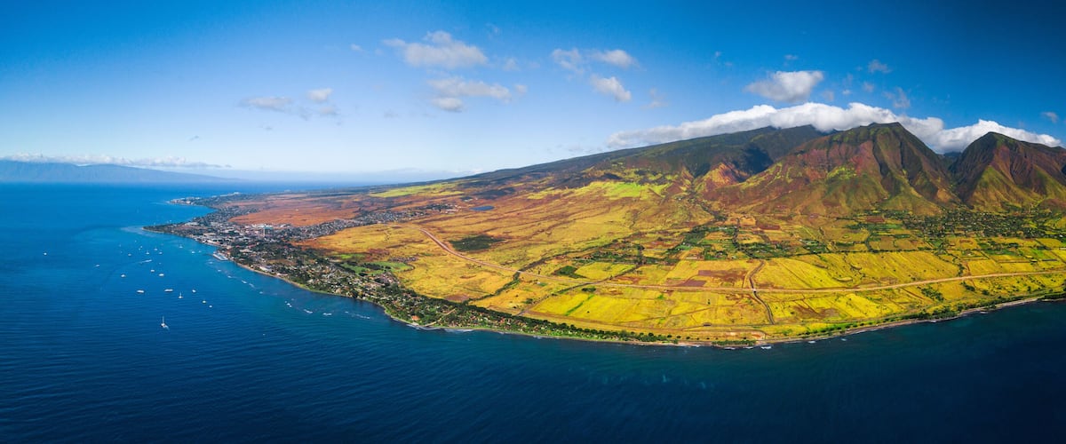 A volcanic island with a coastal town, surrounded by deep blue ocean.