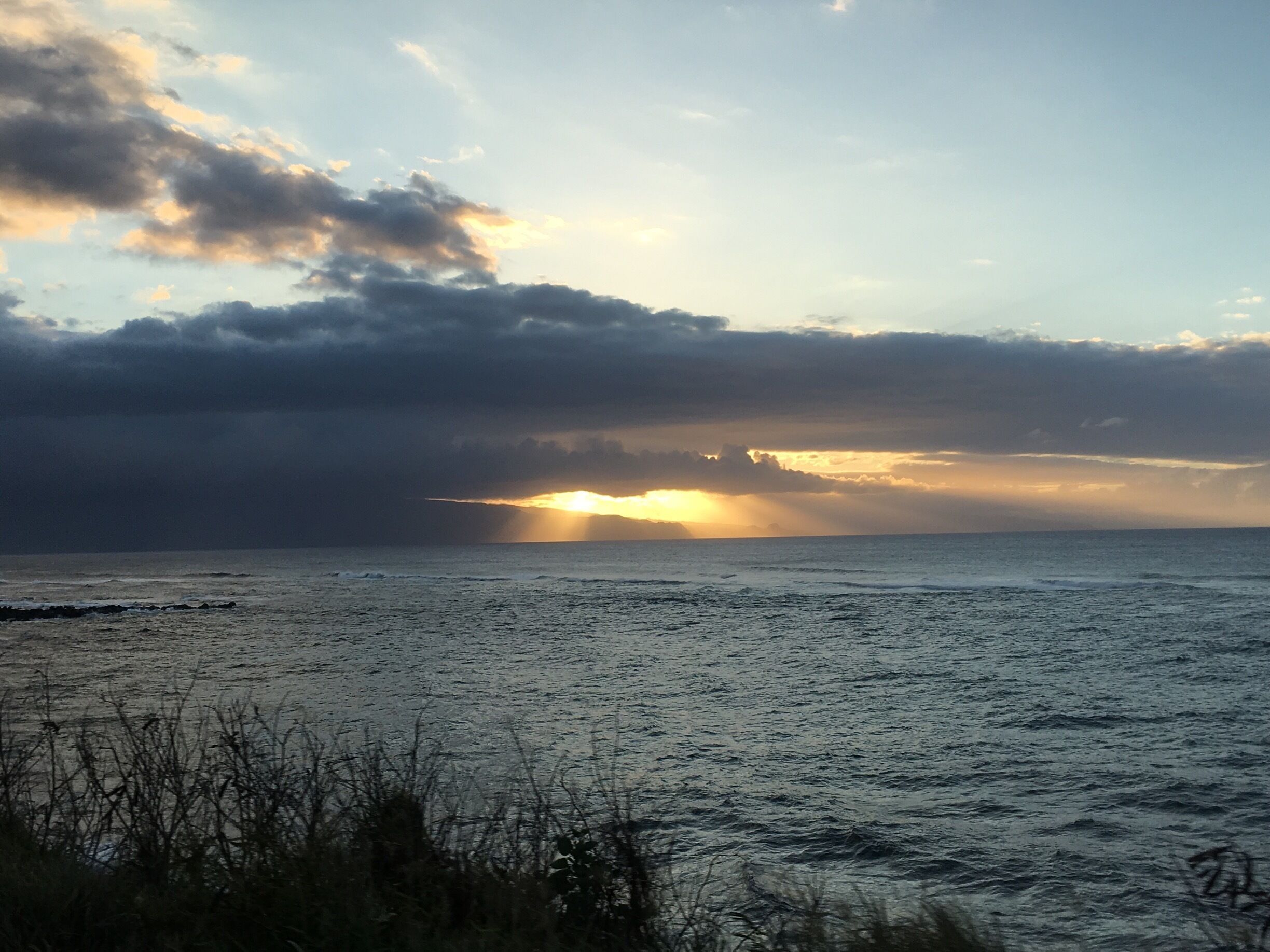 A sunset over a calm sea with clouds in the sky.