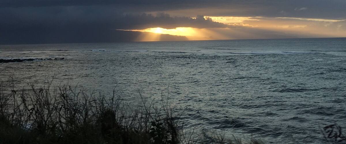 A sunset over a calm sea with clouds in the sky.