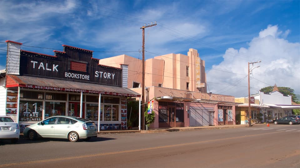 A street with a bookstore named 'Talk Story' and a car parked on the side.
