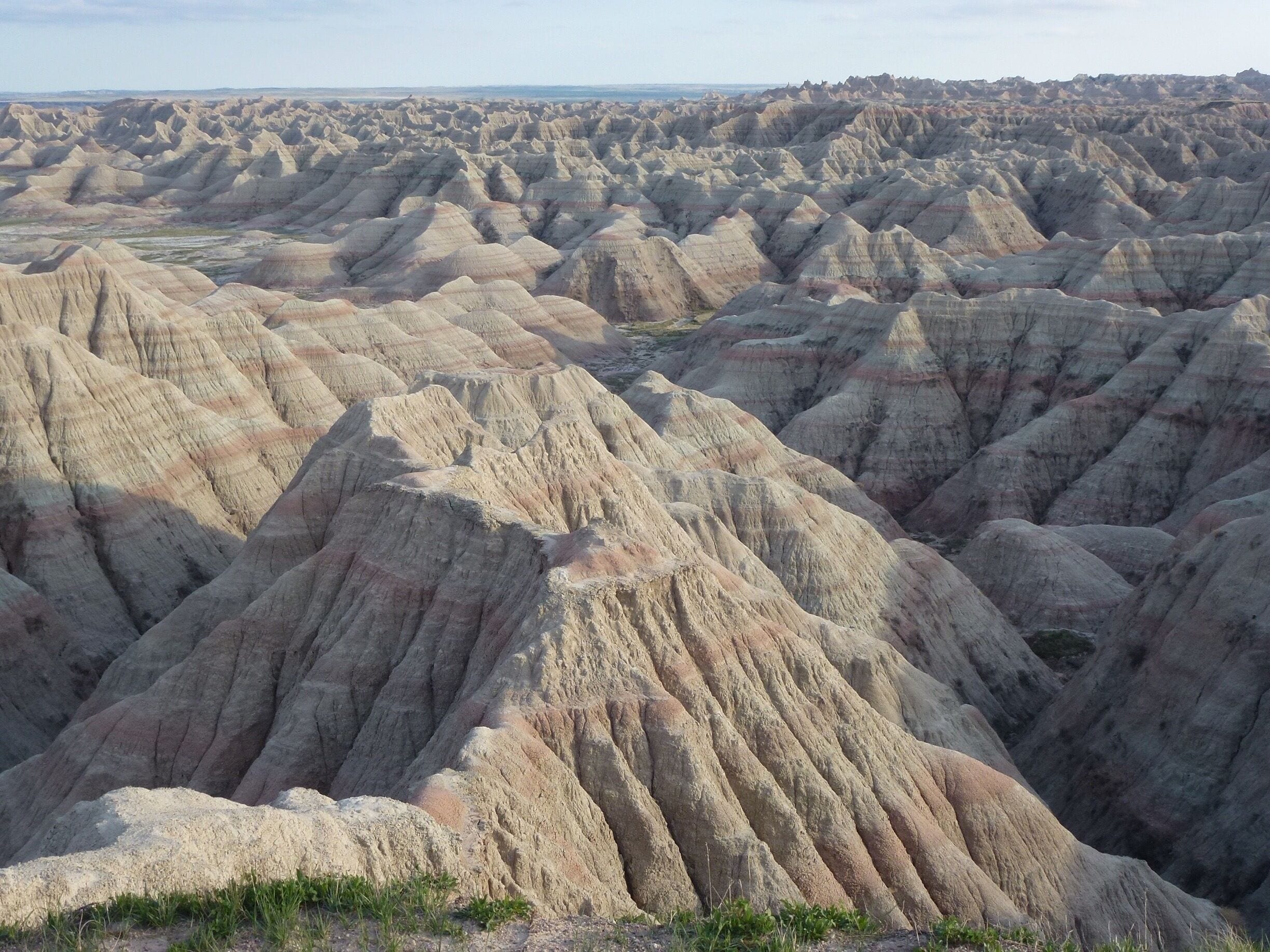 A vast landscape of rugged, eroded hills with distinct layers of sedimentary rock.