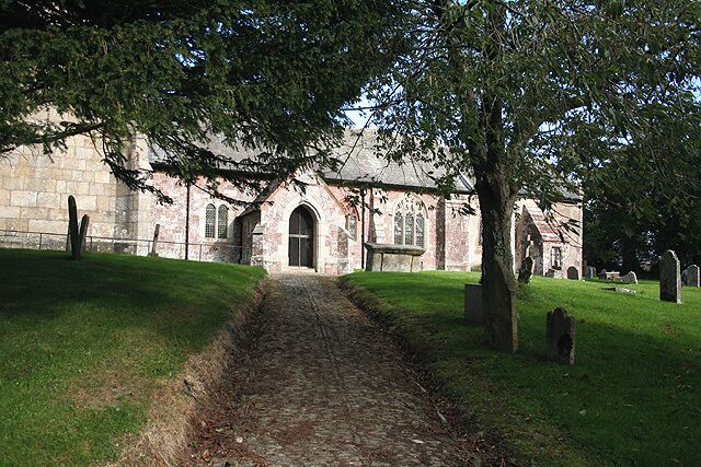 A church with a stone facade, arched windows, and a pathway leading to the entrance.