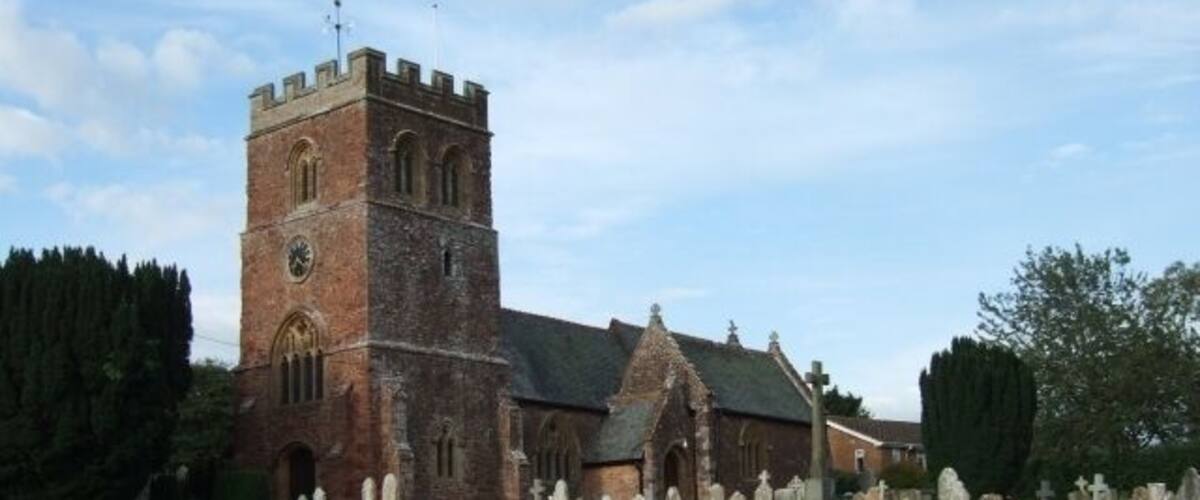 A church with a tall tower and a graveyard in front.