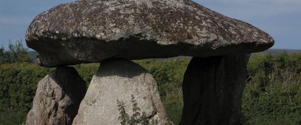 A large stone structure with a mushroom-like top, surrounded by greenery.