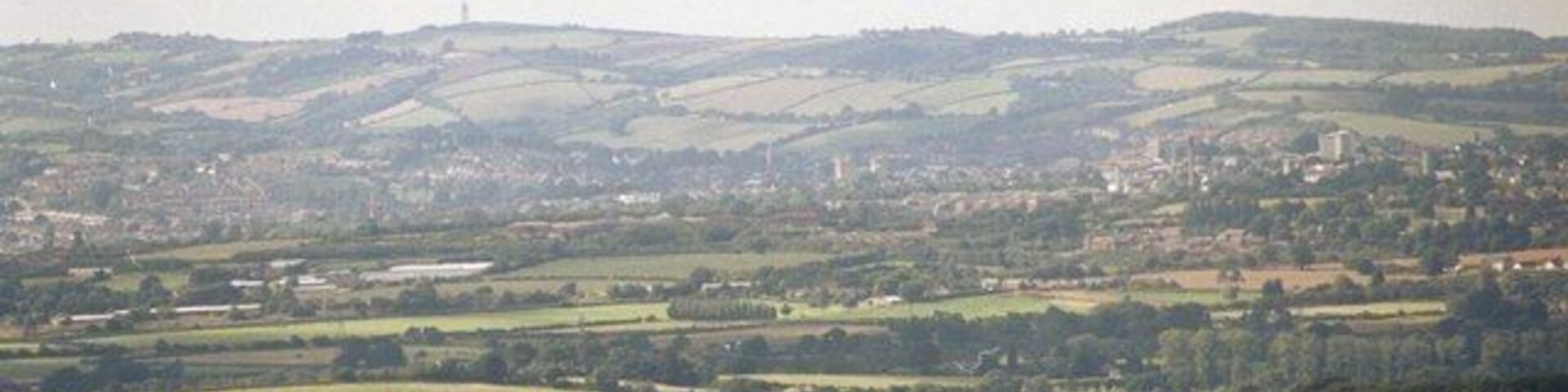 The View from Woodbury Common. Looking slightly north of west from car park W of the B3180. On the skyline is the ttransmitter tower above Redhills SX8992. In centre are Exeter Cathedral towers SX9292 and to the right Exe