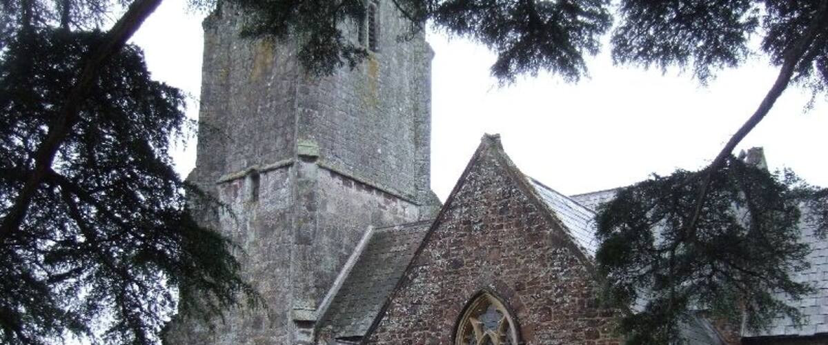 A historic church with a tall tower and a stone building with pointed arches.