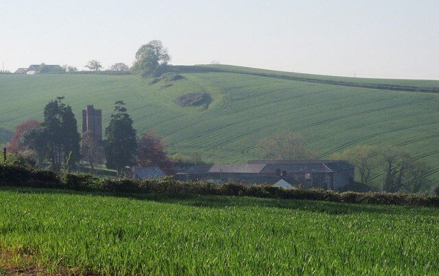 A green field with a building and trees in the background.