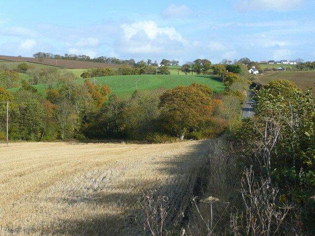 A rural landscape with rolling hills, fields, and scattered trees.
