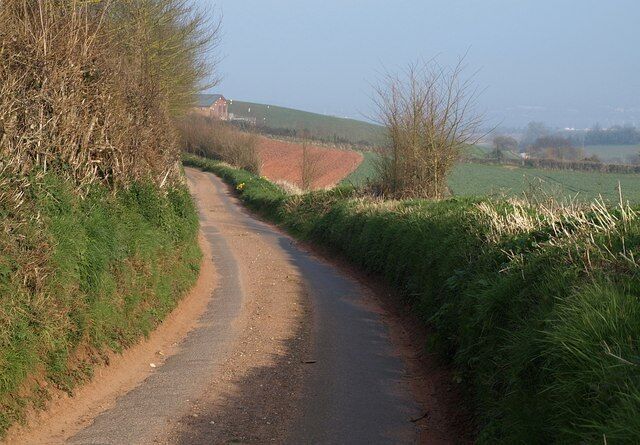 Kenn Lane. Kenn Lane, arriving from Willsworthy Cross, heads towards Exminster. Appearing around the bend is 989547.