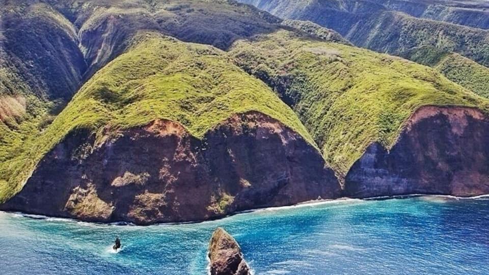 A coastal landscape with green hills and clear blue waters.
