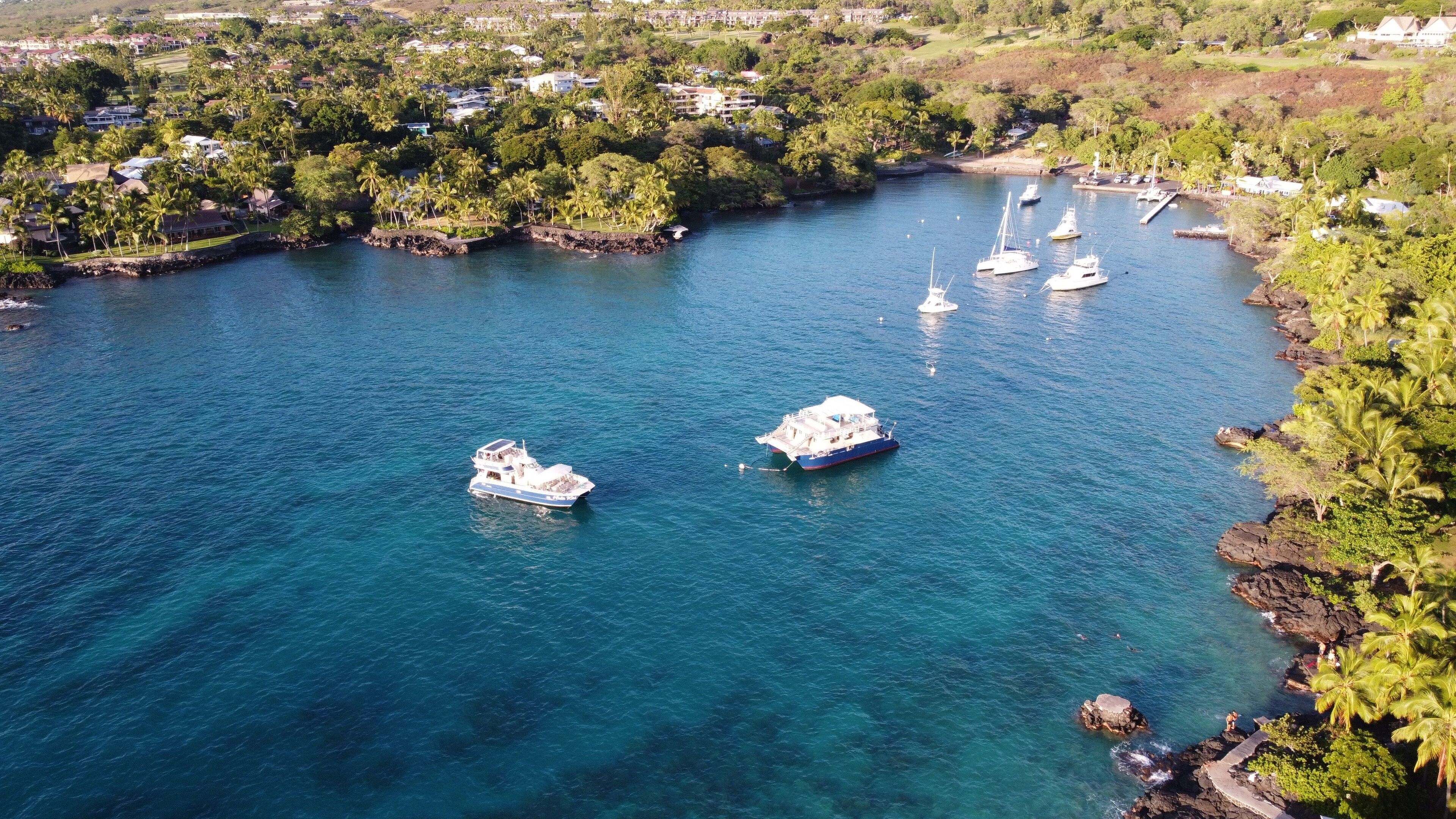 Aerial shot of Keauhou bay in Kailua Kona with boats on water surface and surrounded by vegetation