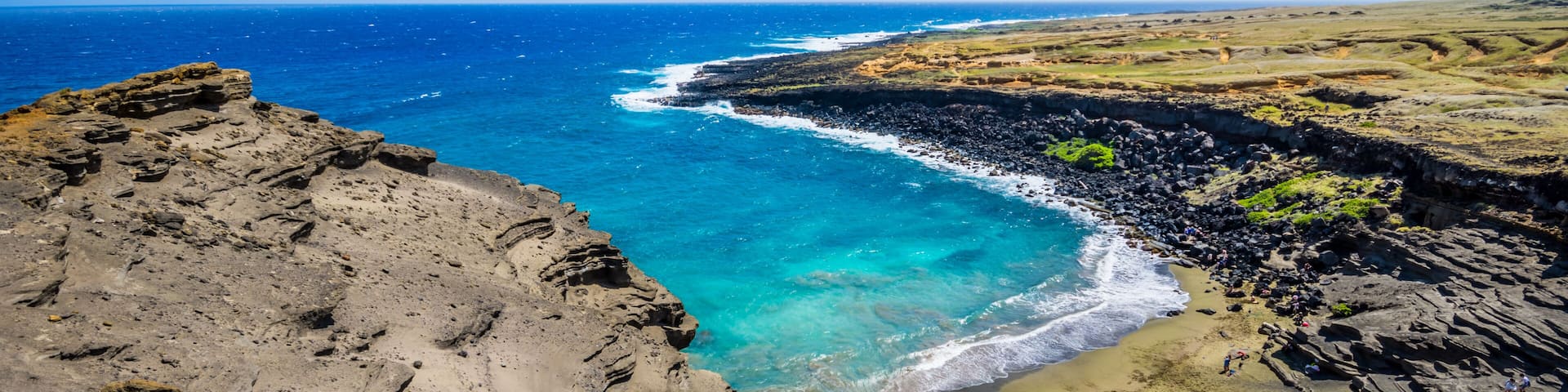 A coastal landscape with a rocky shoreline, clear blue waters, and a distant horizon.