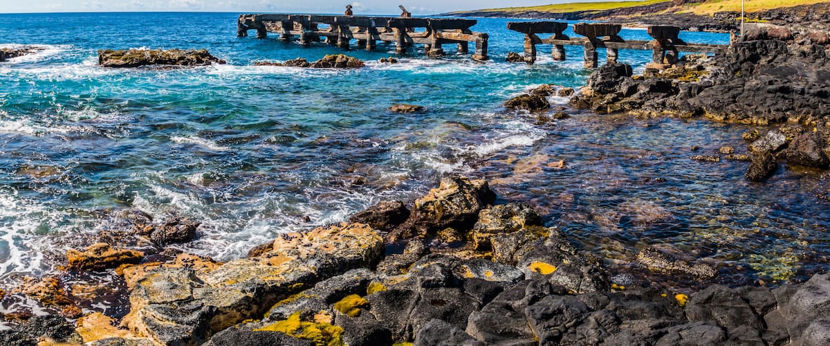 A rocky coastline with a wooden pier extending into the sea.