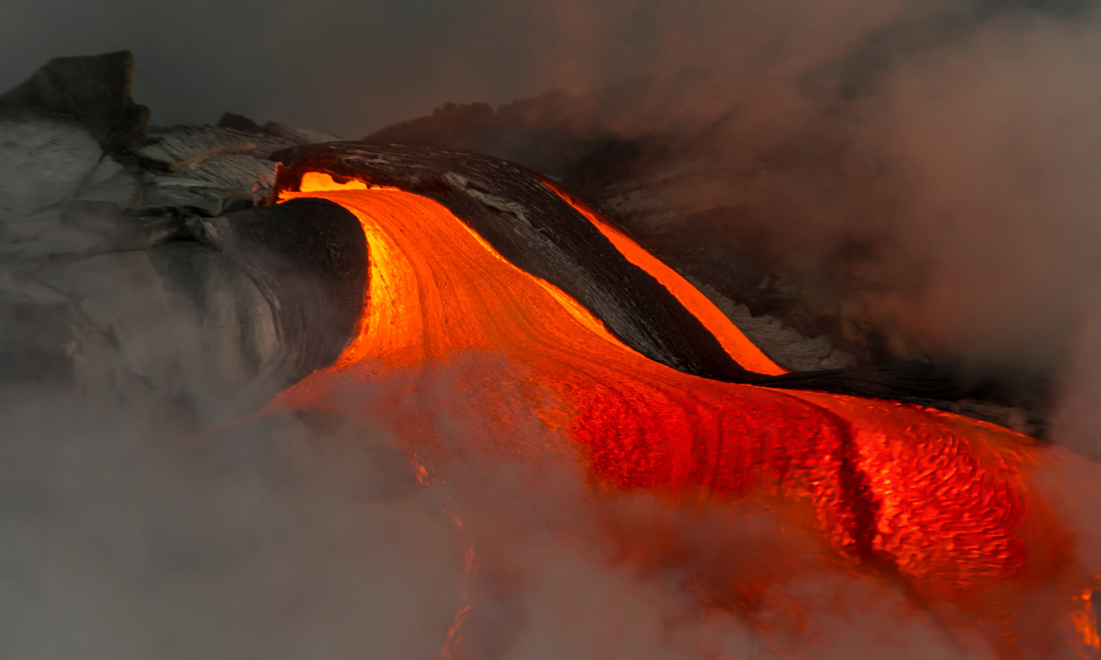 A flowing lava stream with a dark, rocky foreground and a glowing orange glow.