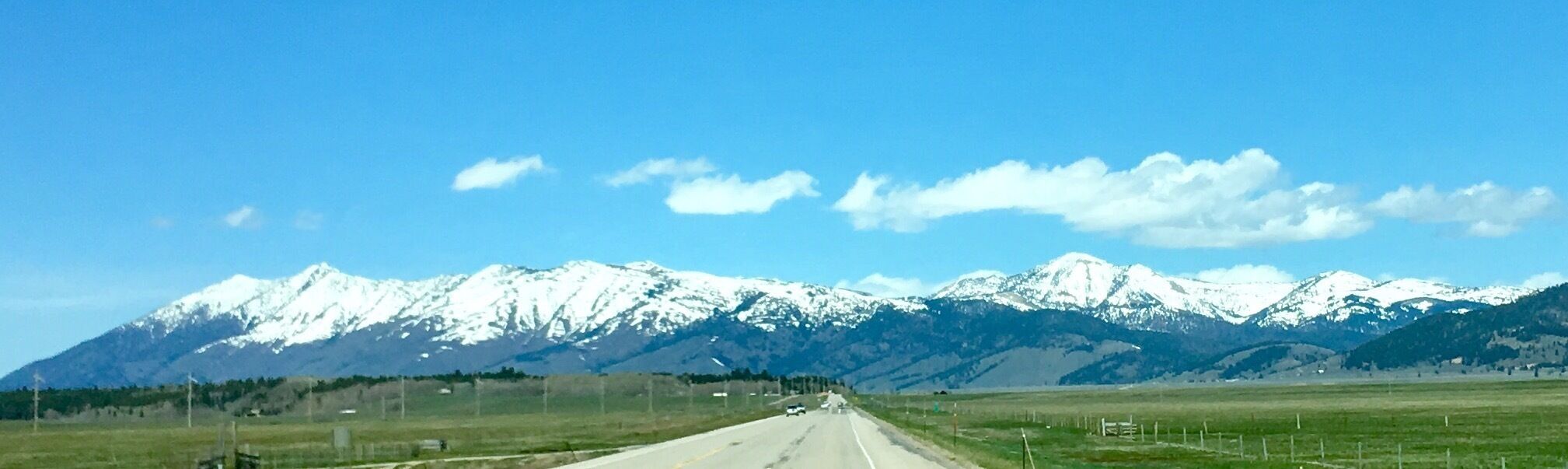 Una carretera que se dirige hacia montañas nevadas bajo un cielo despejado.