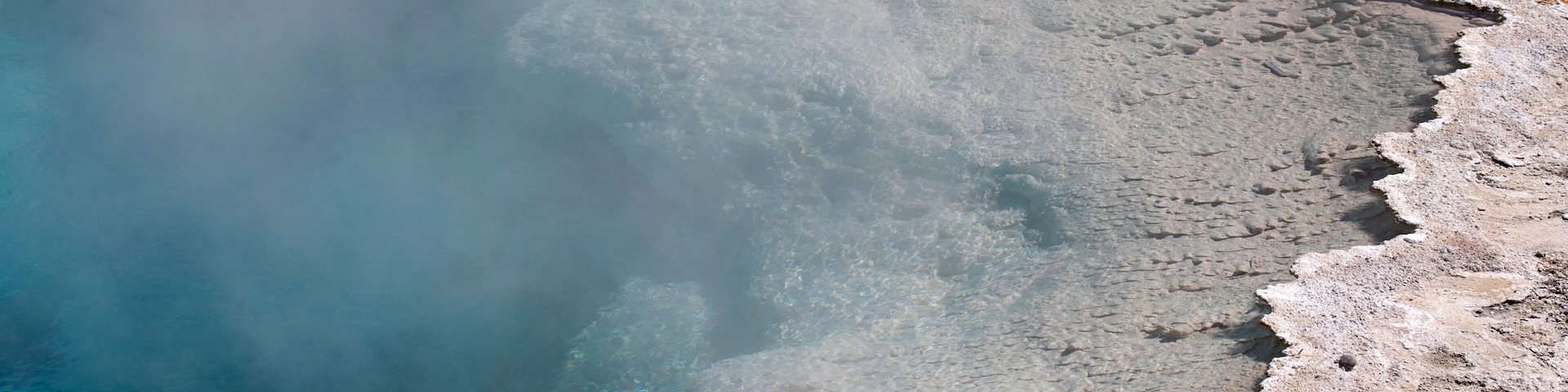 Vista aérea que muestra un área geotérmica con depósitos minerales y un cuerpo de agua.