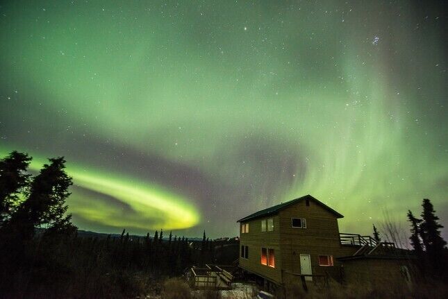 A house under a green aurora display.