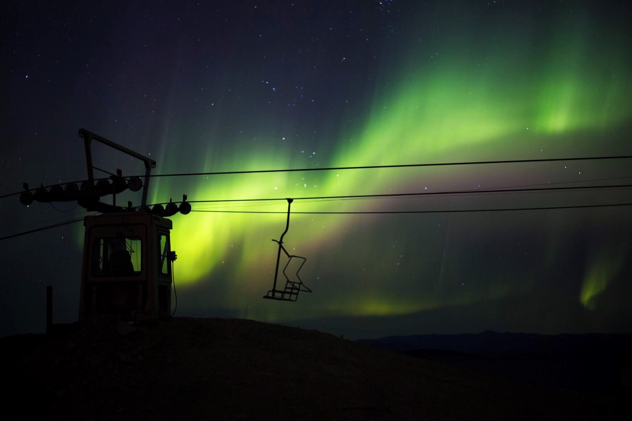 A ski lift against a night sky with the Northern Lights.