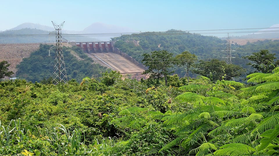 A hydroelectric dam surrounded by lush greenery and hills.