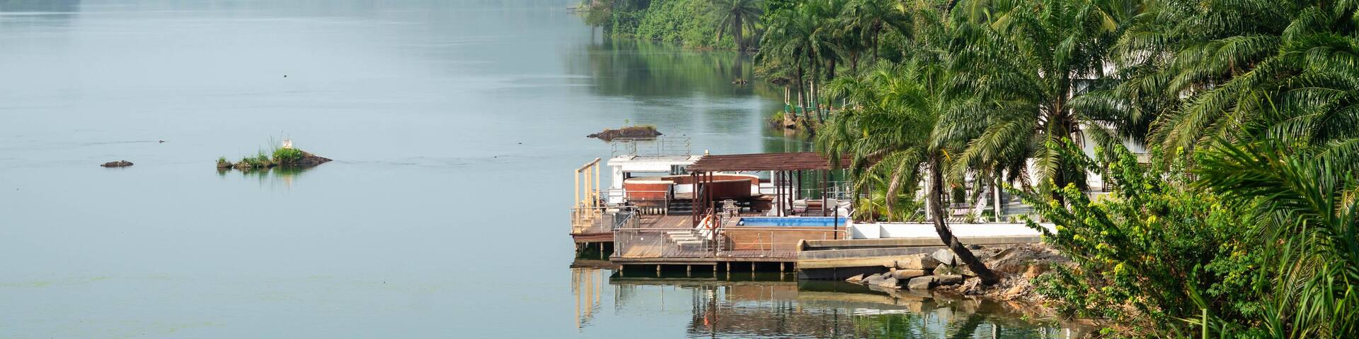 Wooden dock emerging from greenery and floating above the Volta River