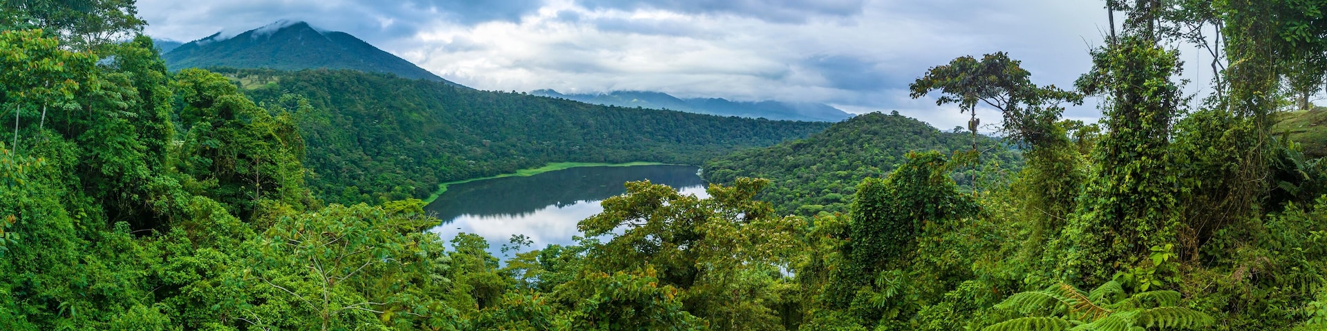 A lush green valley with a lake and a mountain in the background.