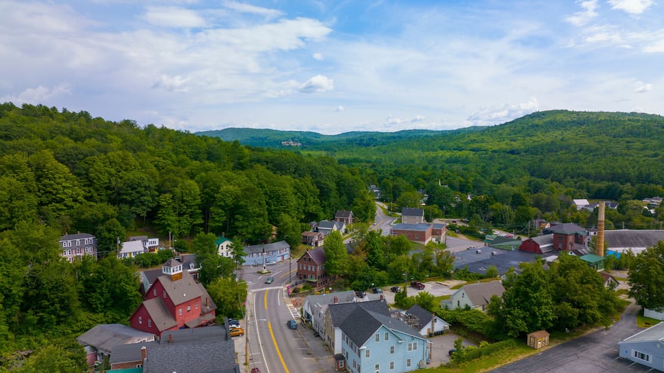 A town with a river, surrounded by hills and dense forests.