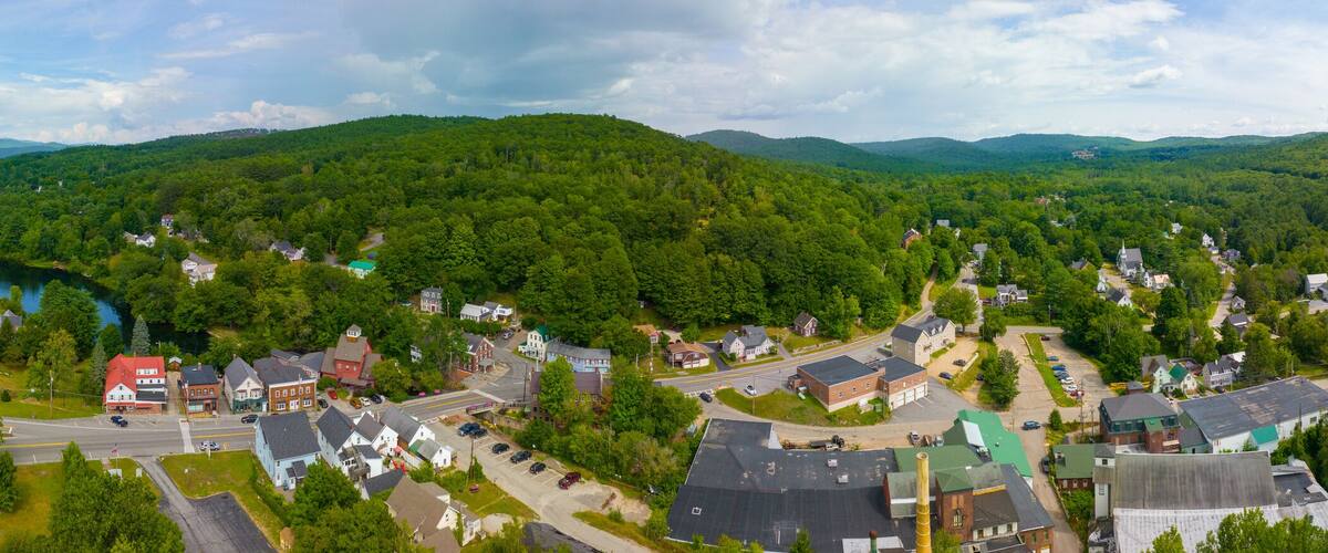A town nestled in a valley with a river running through it, surrounded by lush green hills.