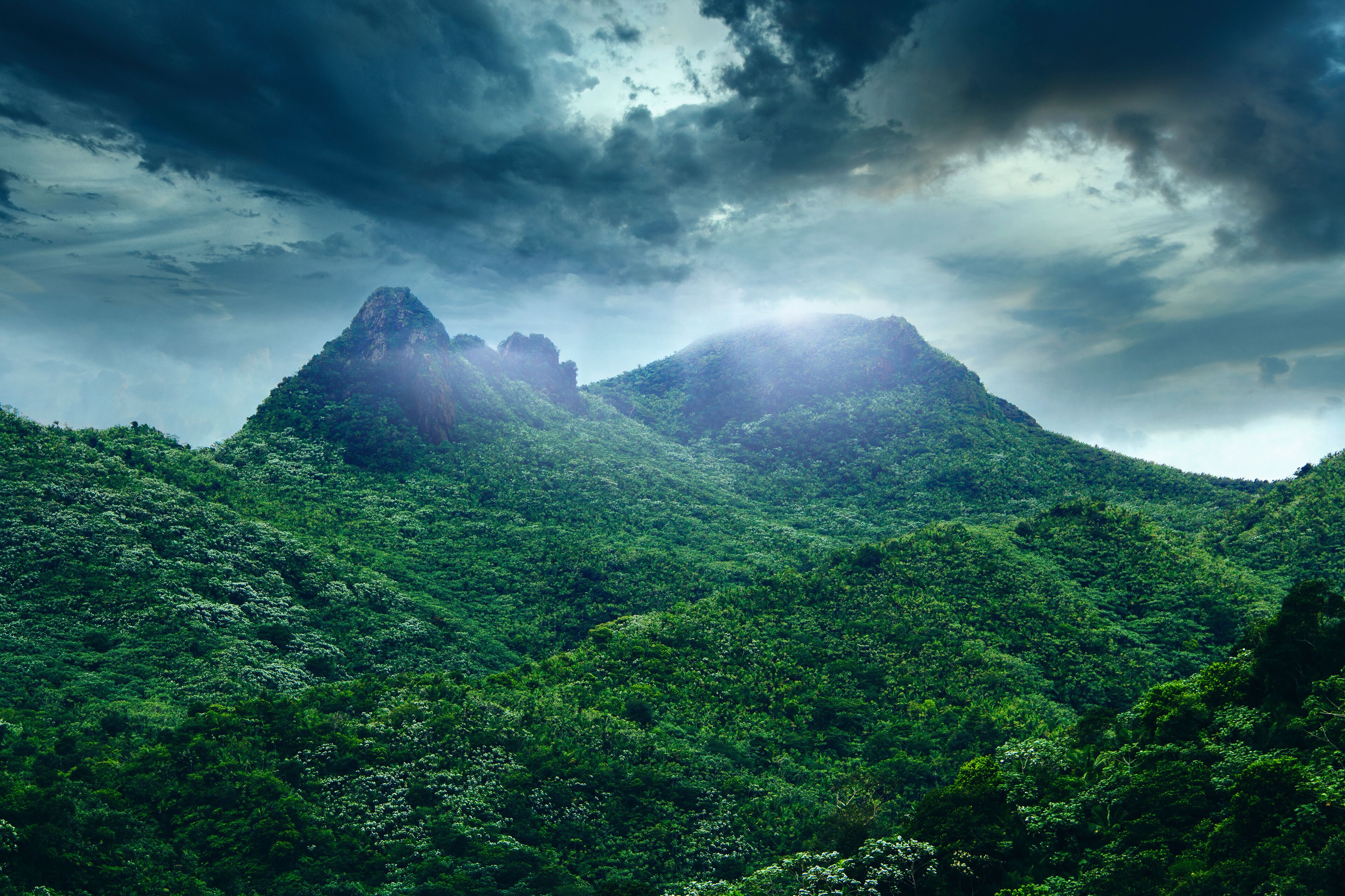 A lush green mountain range under a cloudy sky.