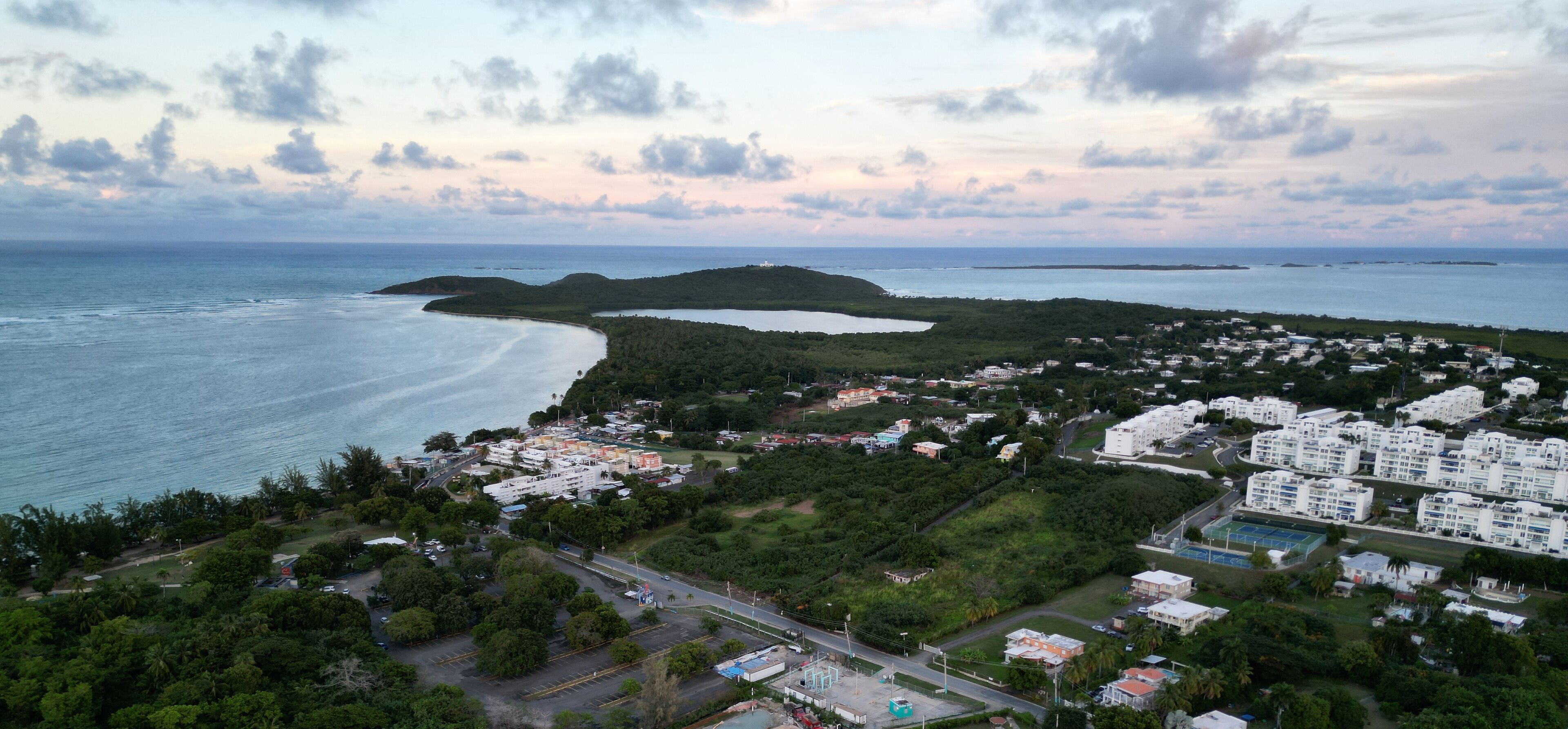 A coastal town with a beach, residential buildings, and a hilly landscape.