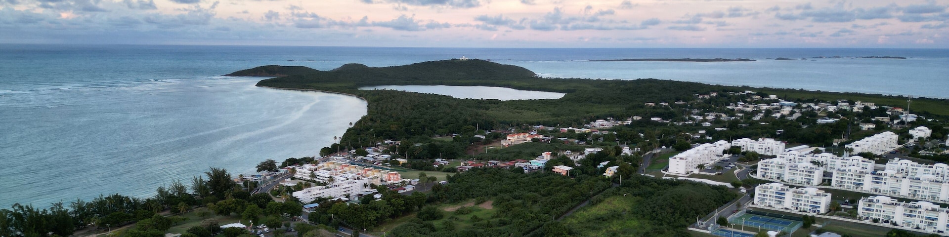 A coastal town with a beach, residential buildings, and a hilly landscape.