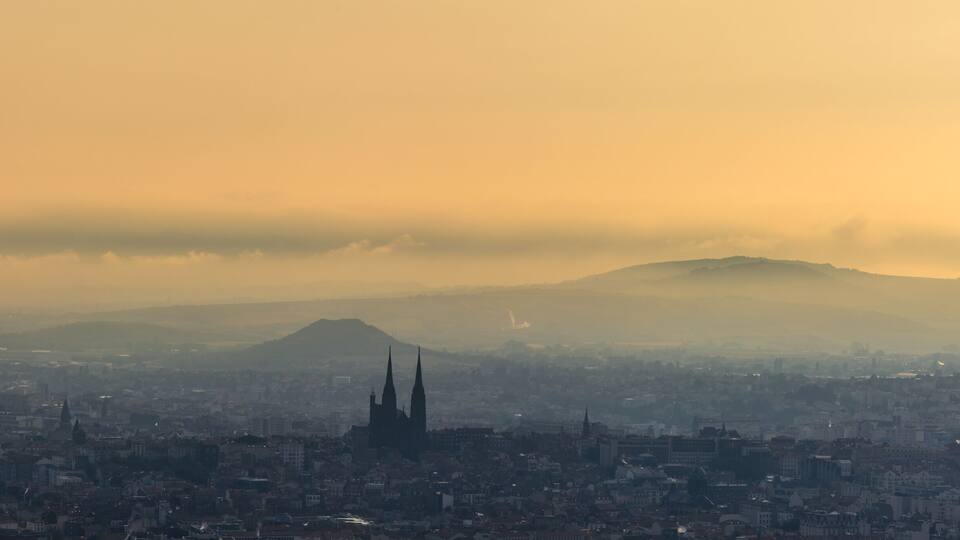 A cityscape with a prominent cathedral and a mountain in the background.