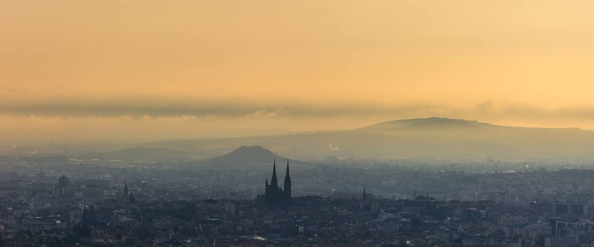 A cityscape with a prominent cathedral and a mountain in the background.