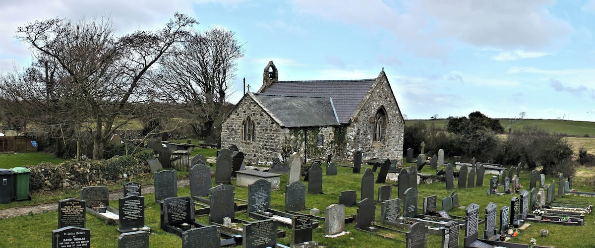 A church surrounded by a cemetery with numerous gravestones.
