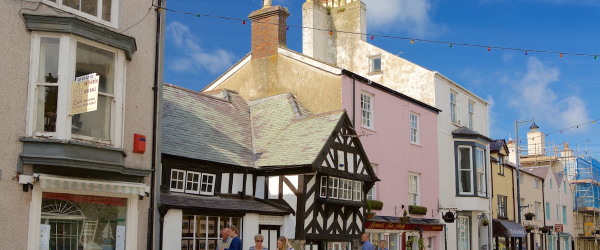 A street with traditional half-timbered houses, a pink building, and a sign for a shop.